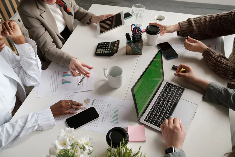 A modern workspace showing hands analyzing marketing data on a laptop and paper documents.